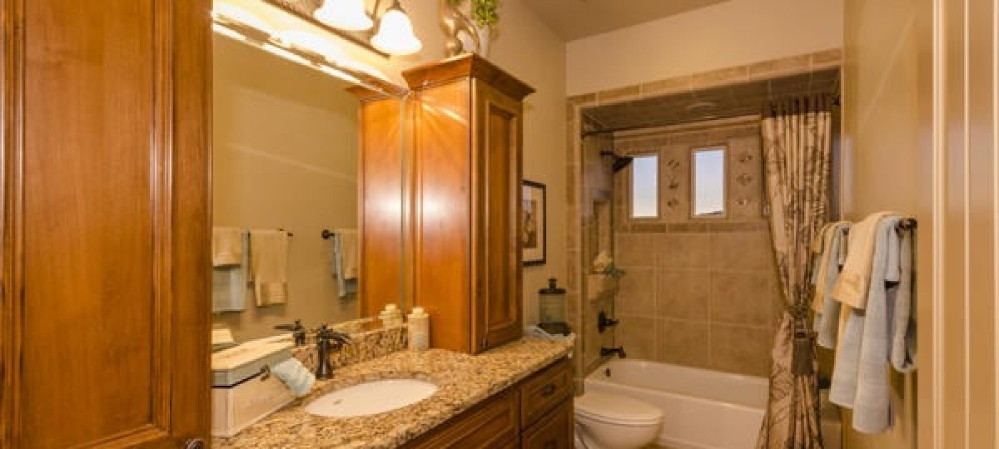 a newly remodeled bathroom with bright lights and oak cabinets