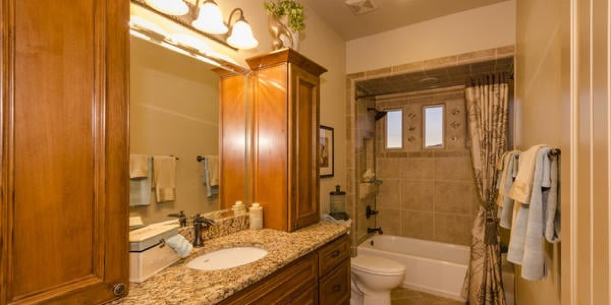 a newly remodeled bathroom with bright lights and oak cabinets